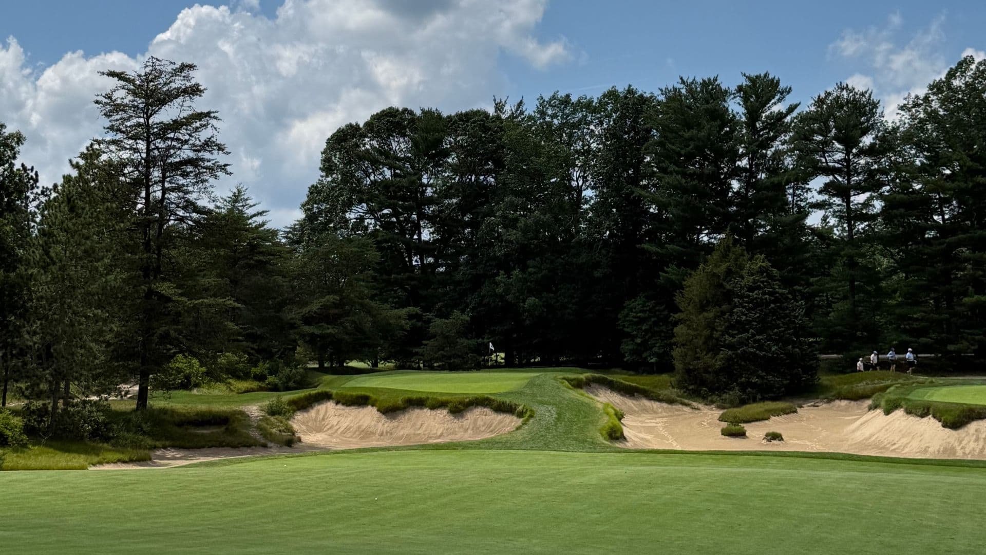 A historic white clubhouse tower and green mailbox with pine tree emblem are nestled among mature trees at Pine Valley Golf Club.